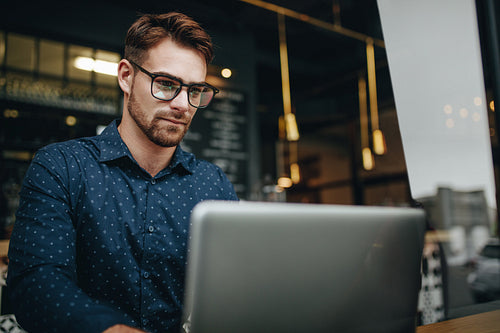 Man working on laptop sitting at a cafe