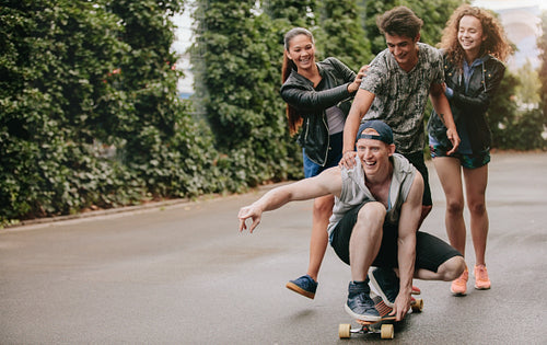 Group of friends having fun outdoors with skateboard