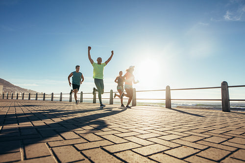 Group of young people running along seaside