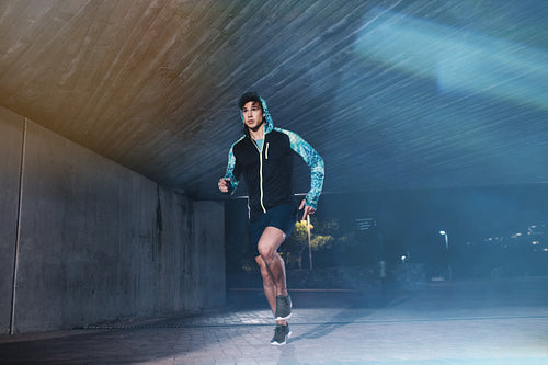Fit young man jogging in the city at night