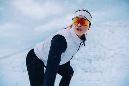 Female athlete stretching before run on snowy terrain in winter sportswear