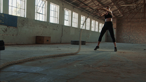 Strong woman working out with battle rope