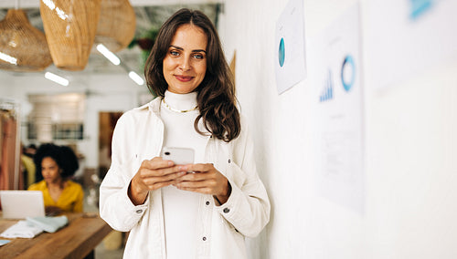 Making connections using technology: Woman using a phone in a clothing boutique