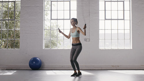 Woman exercising with jumping ropes at fitness studio