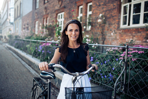 Beautiful woman with a cycle walking down the city road