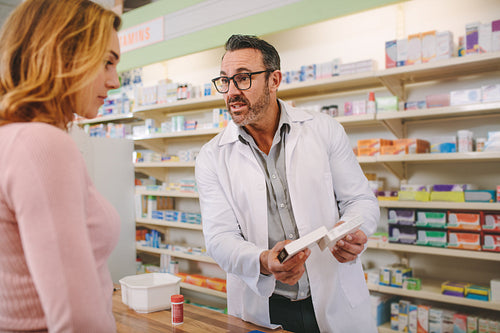 Pharmacist with a medicine box giving advice to customer