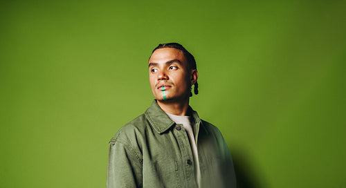 Artistic man portrait in the studio with face paint and braided style