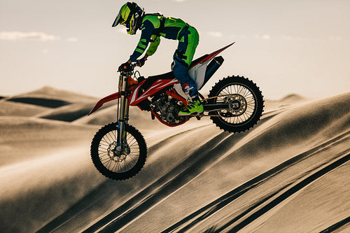 Motocross biker riding bike in the desert