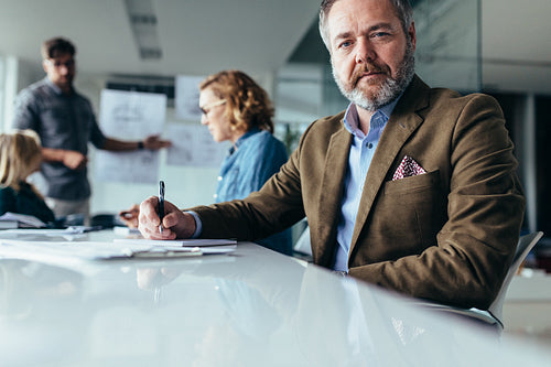Mature man sitting in board room during presentation
