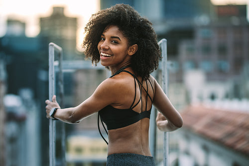 Portrait of female athlete standing on rooftop looking back