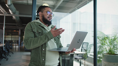 Business man holding a laptop and discussing with his team in an office
