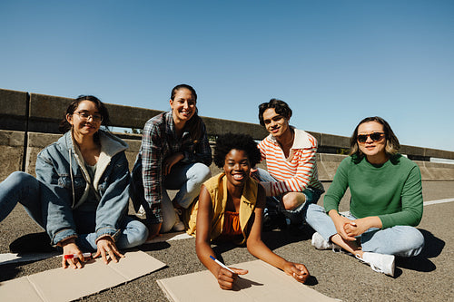 Smiling group of five activists sitting on the pavement during a peaceful demonstration