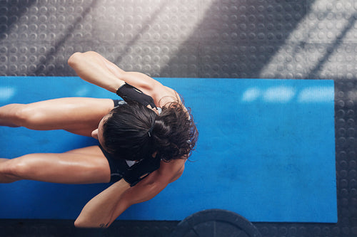 Muscular young woman doing sit ups on an exercise mat