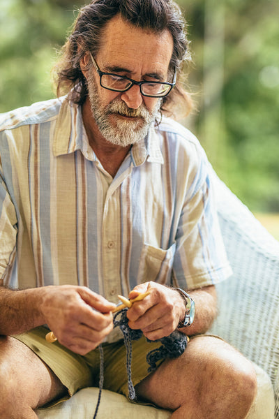 Senior man knitting while sitting on chair