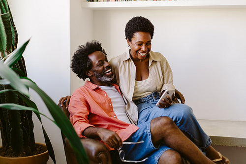 Quality time together: Happy couple sitting on the sofa, browsing a smartphone