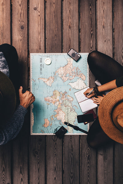Couple planning vacation sitting by the world map.