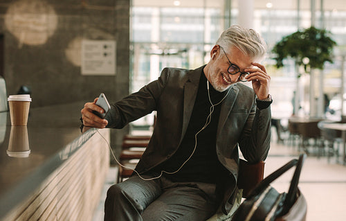 Businessman talking on phone with earphones at cafe