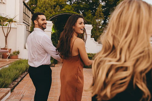 Couple greeting their friends outside a luxury hotel