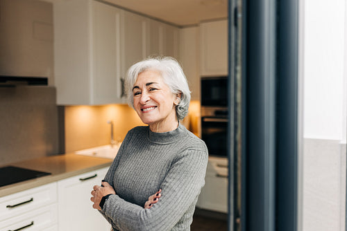 Silver-haired woman smiling at the camera at home