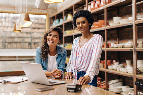 Successful young ceramists smiling at the camera in their shop
