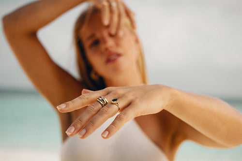 Close-up of a hand adorned with elegant gold rings on a sunny beach