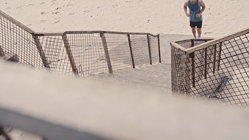 Muscular man working out on the steps at the beach