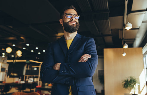 Cross-armed businessman looking away thoughtfully