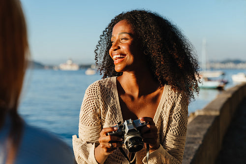 Young woman holding camera at Mureta Da Urca waterfront
