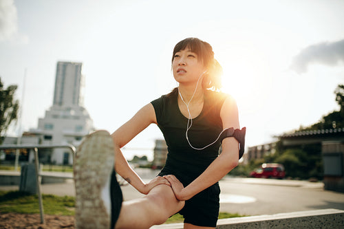 Sporty woman stretching her leg in park