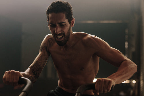 Fit man using exercise bike at the gym