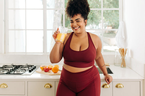 Body positive woman with glass of juice at kitchen