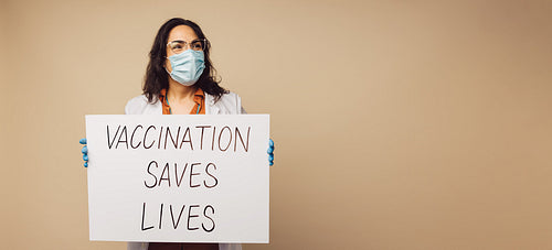 Doctor showing "Vaccination Saves Lives" signboard