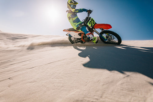 Professional motocross biker riding on sand dunes