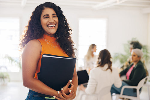 Happy young businesswoman standing in a boardroom