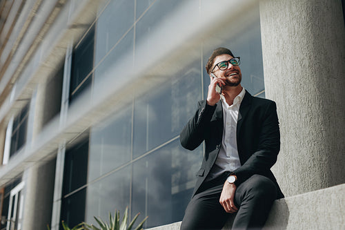 Businessman talking over mobile phone sitting outdoors
