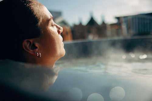 A steam-filled spa surrounds the woman in a quiet wellness moment.