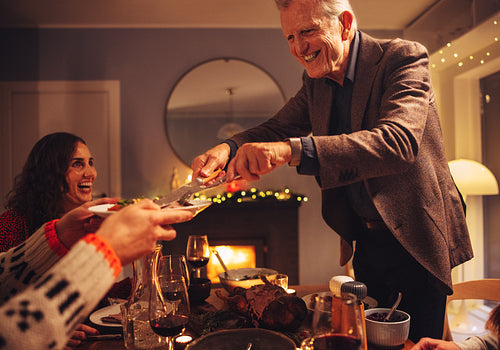 Senior man serving Christmas dinner to family