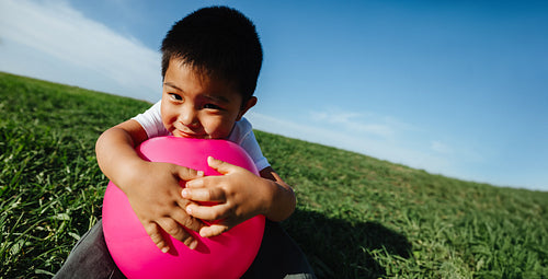 Child playing with pink ball in grassy field