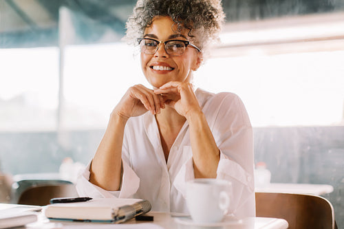Happy businesswoman sitting alone in a cafe
