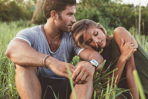 Relaxed young couple sitting on grass field