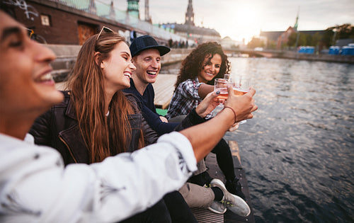 Group of young people having drinks at lake