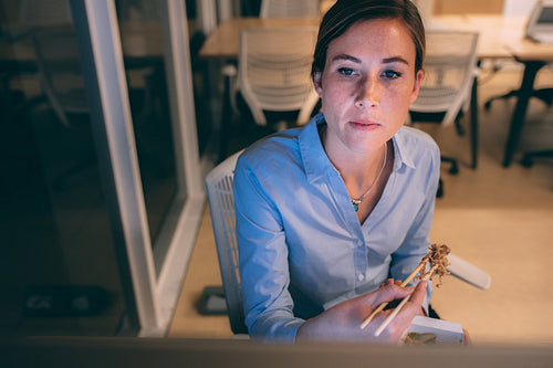 Woman entrepreneur sitting in office having dinner
