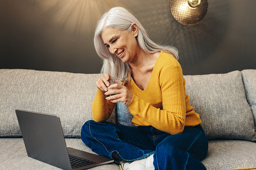 Senior woman working remotely from her couch at home