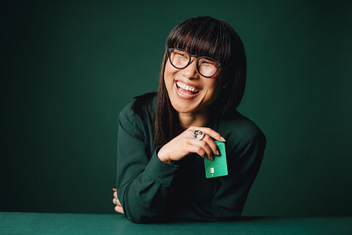 Mature woman laughing with bank card for exclusive membership in studio