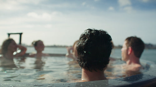 Friends relaxing in an outdoor hot tub at a spa retreat on a sunny day