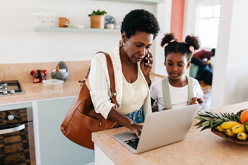 Working mom's morning routine: Woman making work calls with daughter standing by