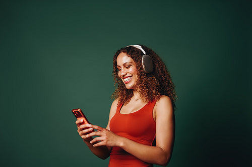 Smartphone in hand, the woman uses headphones for music in the studio