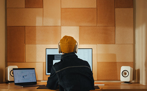 Man works at a computer desk wearing headphones in a creative office space