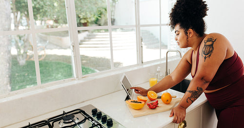 Fitness woman reading recipe on tablet pc in kitchen