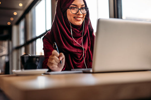 Muslim woman having video chat at cafe